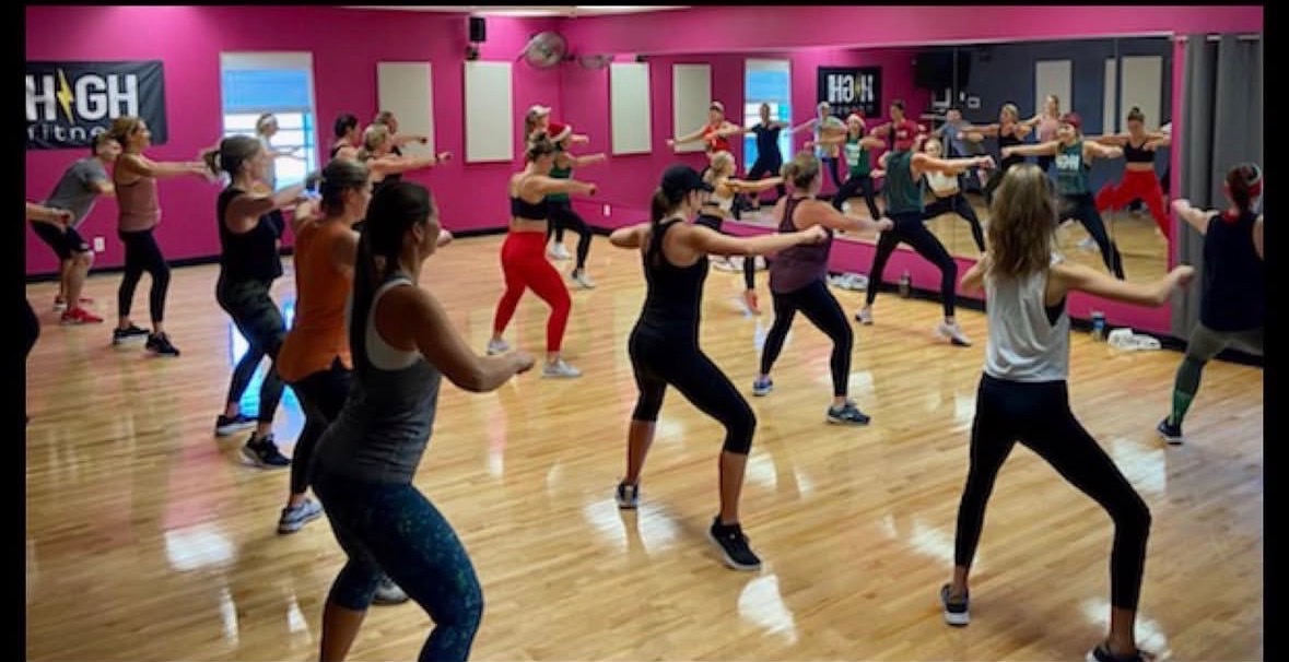 Dance fitness class mid-routine in the mirrored Hilltop Court studio